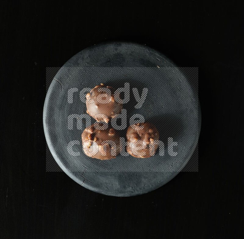 Assorted desserts in a black pottery plate on black background