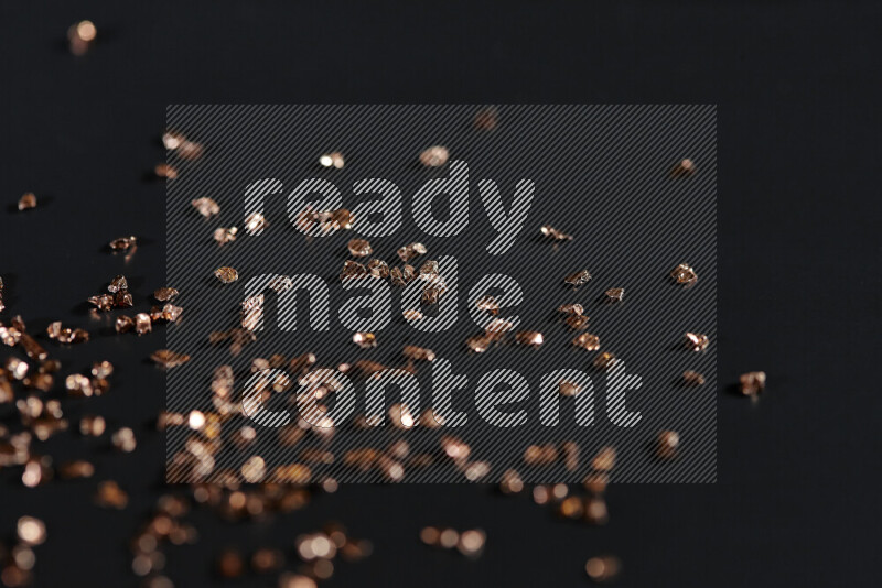 قطع زجاجية برونزية لامعة متناثرة على خلفية سوداء