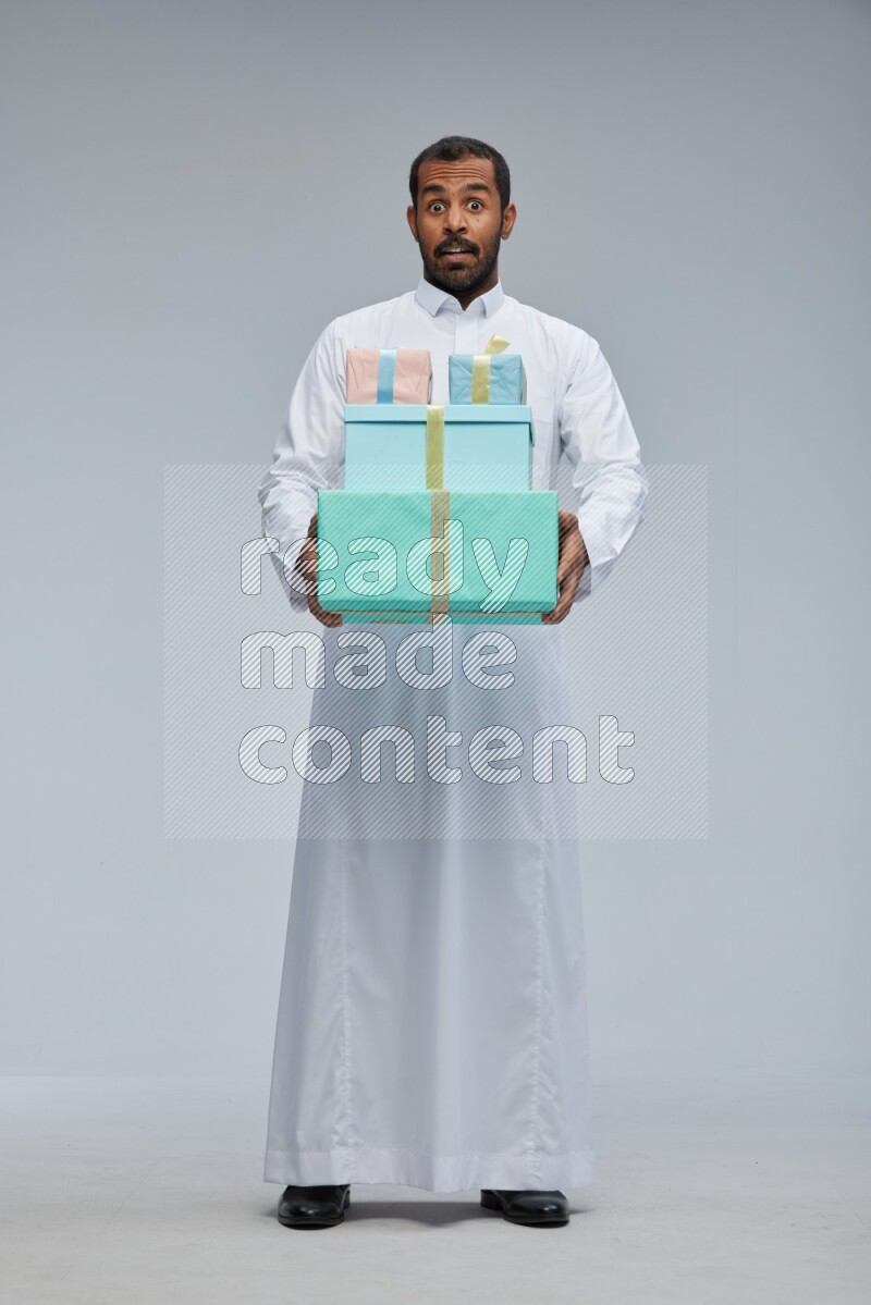 Saudi man Wearing thob standing holding gift box on Gray background