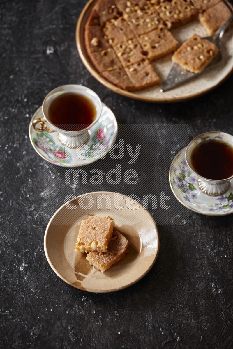 Basbousa with tea in a dark setup