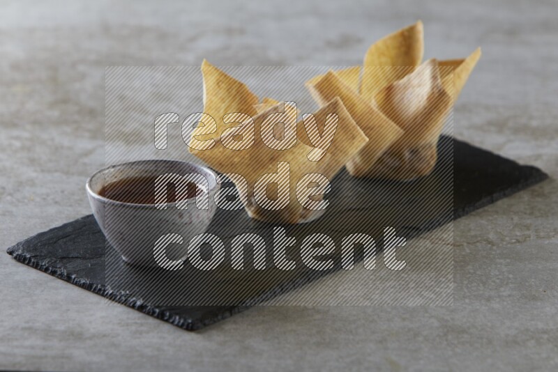 wonton cups with soy sauce ramkin on rectangle slate on grey textured counter top