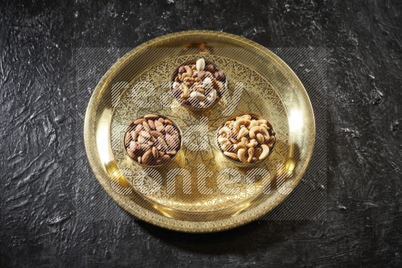 Nuts in metal bowls on a tray in a dark setup