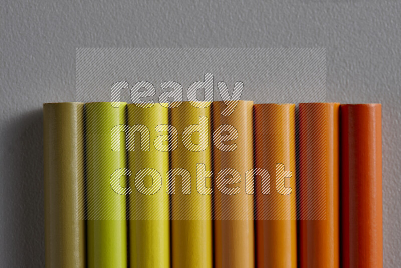 مجموعة من أقلام الرصاص الملونة مرتبة لتعرض تدرجا من اللون الأصفر والبرتقالي علي خلفية رمادية