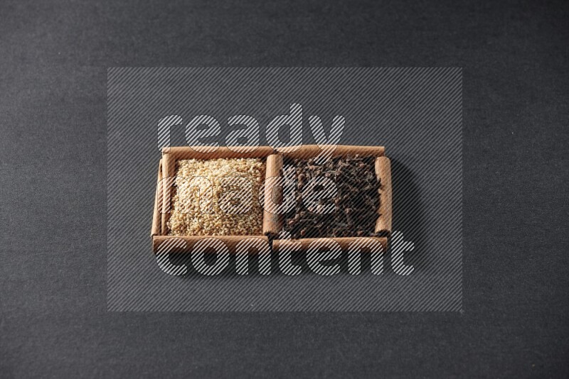 2 squares of cinnamon sticks full of sesame and cloves on black flooring