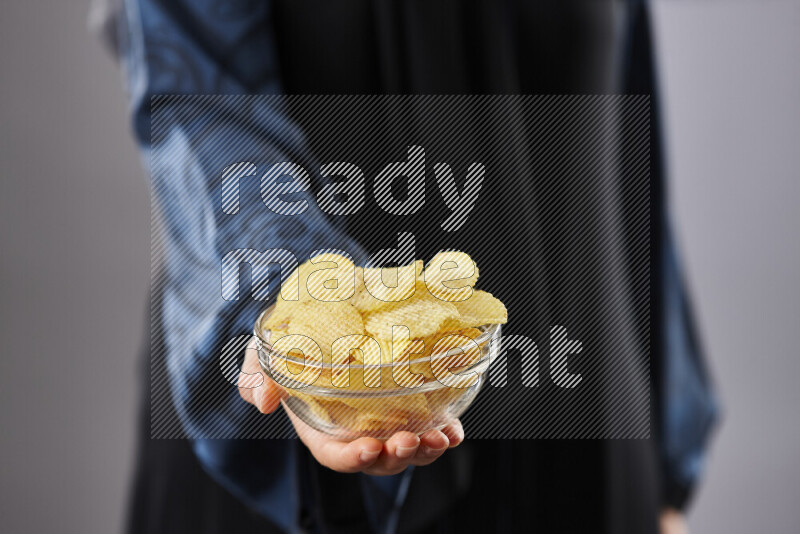 Woman in abaya holding different kinds of snacks in different positions