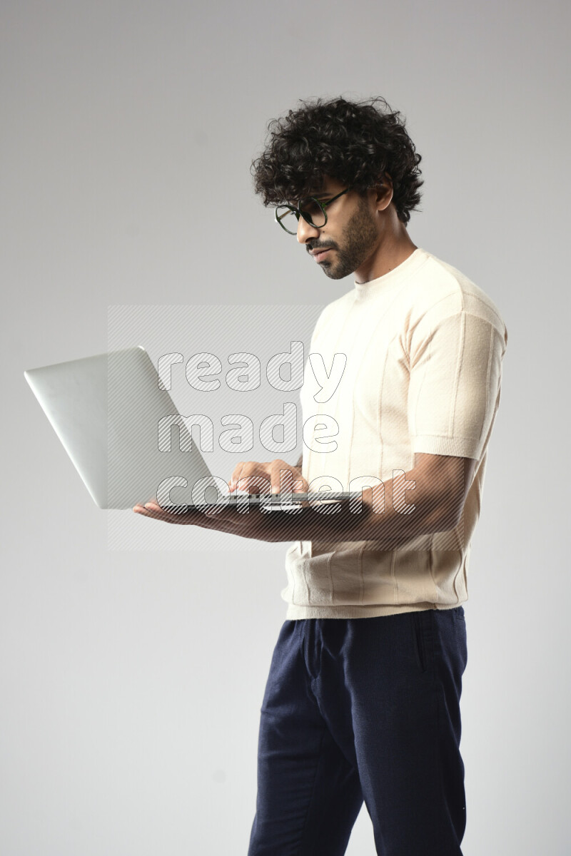 A man wearing casual standing and working on a laptop on white background