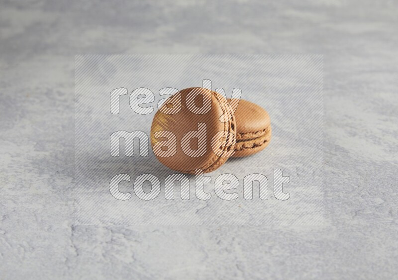 45º Shot of two Brown Coffee macarons  on white  marble background