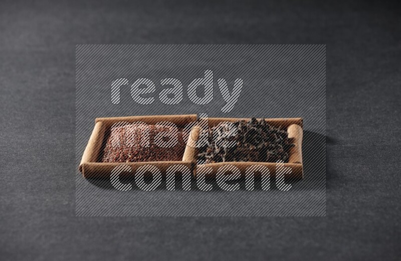 مربعان من أعواد القرفة ممتلئان بحب الرشاد والقرنفل علي خلفية سوداء