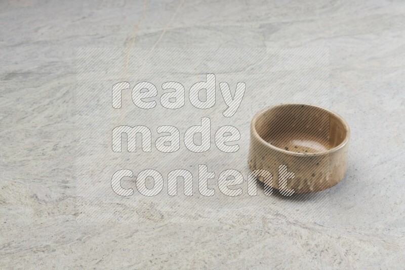 A small beige pottery bowl on grey marble background