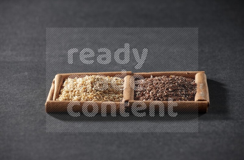 2 squares of cinnamon sticks full of flaxseeds and sesame on black flooring