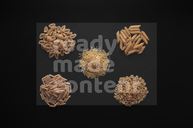 Different pasta types in bunches on black background