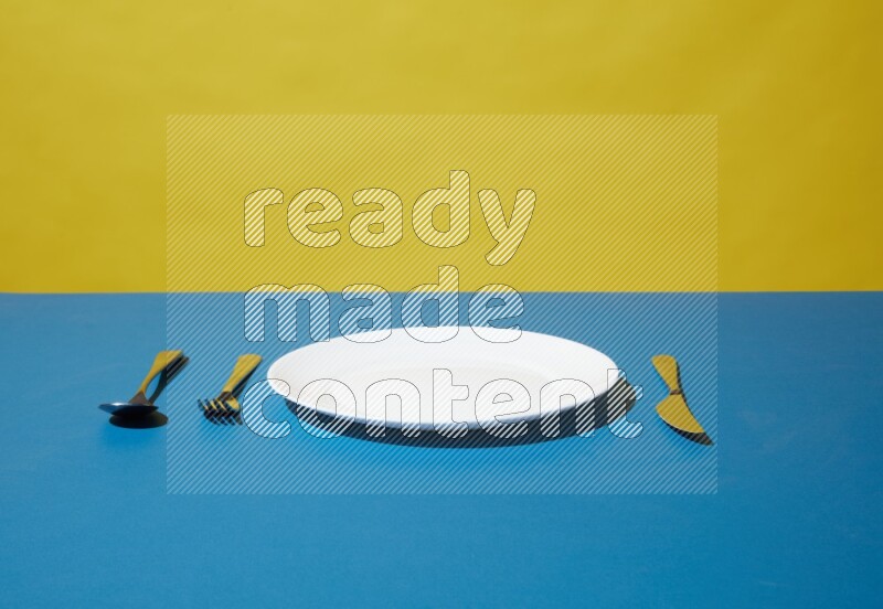 white plate and silverware on yellow and blue background