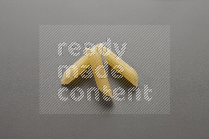 Mini penne pasta on grey background