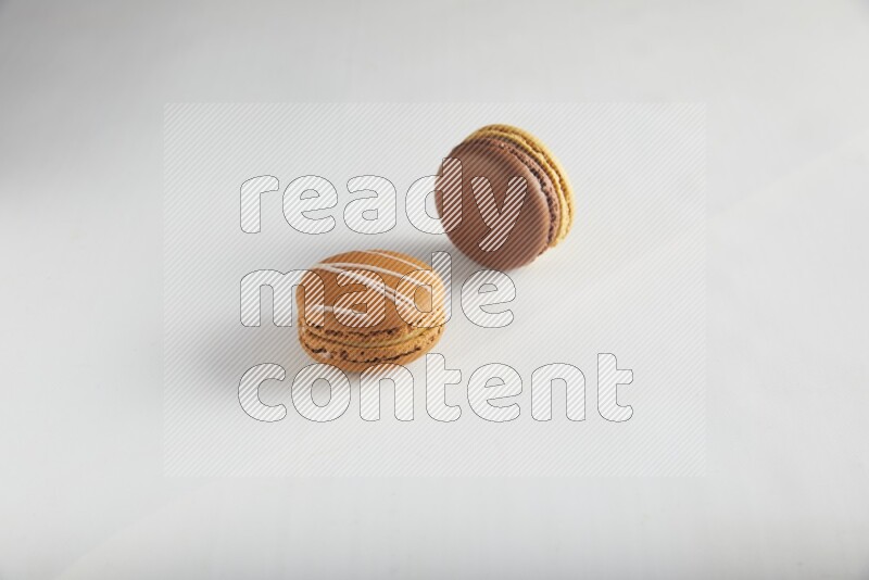 45º Shot of of two assorted Brown Irish Cream, and Yellow, and Brown Chai Latte macarons on white background