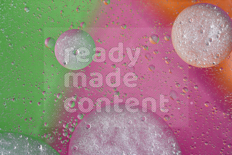 لقطات مقربة لفقاعات من الزيت على سطح الماء باللون البرتقالي والأخضر والوردي