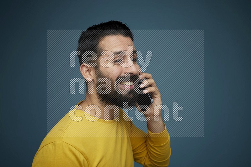 A man having a calling in a blue background wearing a yellow shirt