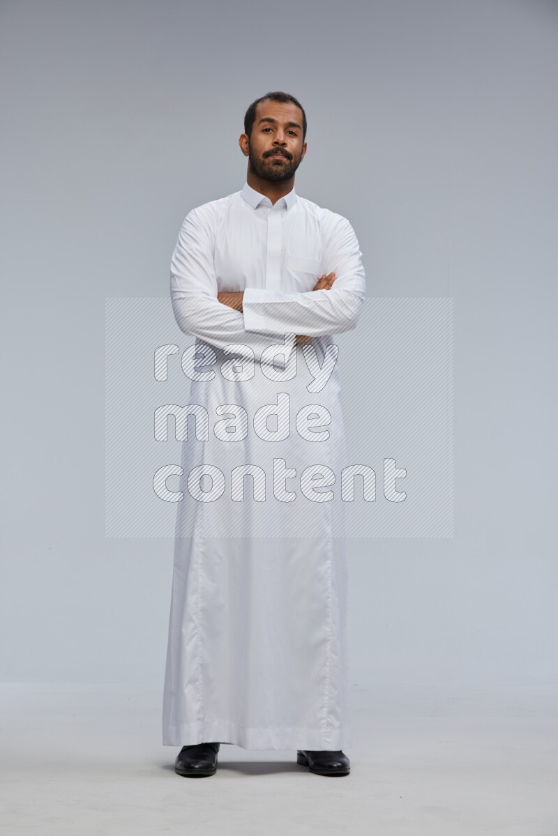 Saudi man wearing Thob standing with crossed arms on Gray background