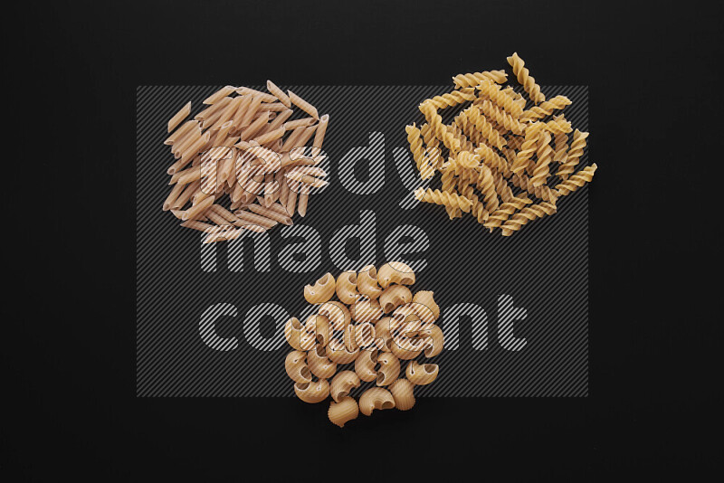 Different pasta types in bunches on black background