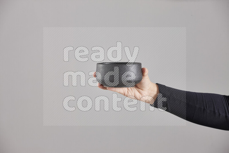 A woman in black abaya holding different pottery essentials in different positions