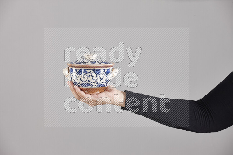 امرأة ترتدي عباءة سوداء تحمل أدوات فخارية مختلفة في أوضاع متعددة