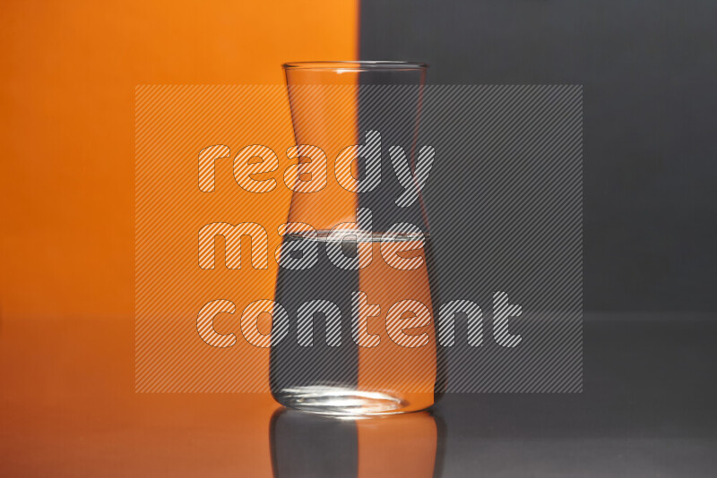 تظهر الصورة أواني زجاجية ممتلئة بالماء موضوعة على خلفية من اللونين البرتقالي والأسود
