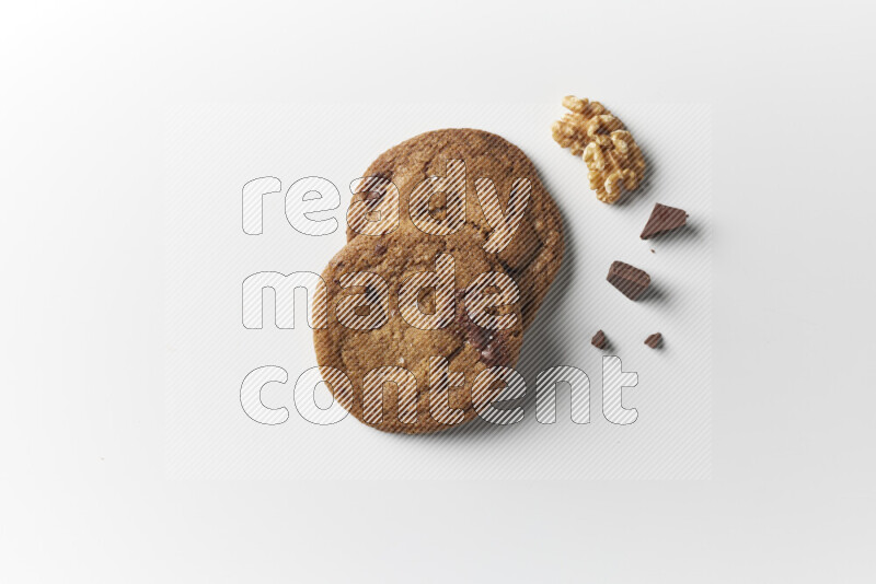 Chocolate chips cookies with chocolate and walnuts beside it on a white background