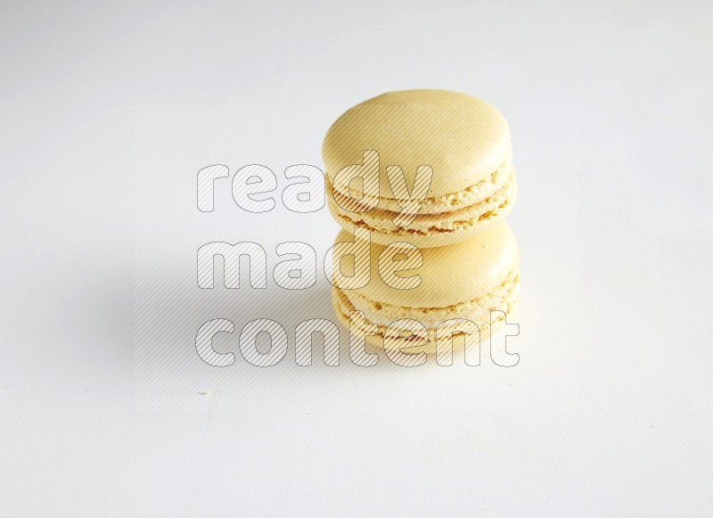 45º Shot of two Yellow Vanilla macarons on white background