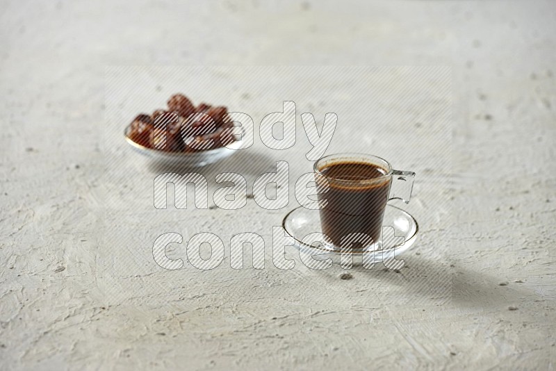 كوب زجاجي من القهوة مع التمر والشاي على خلفية بيضاء