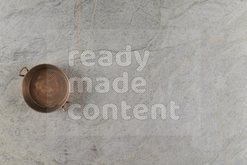A small copper pan on grey marble background