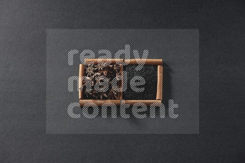 مربعان من أعواد القرفة ممتلئان بحبة البركة السوداء واليانسون النجمي علي خلفية سوداء