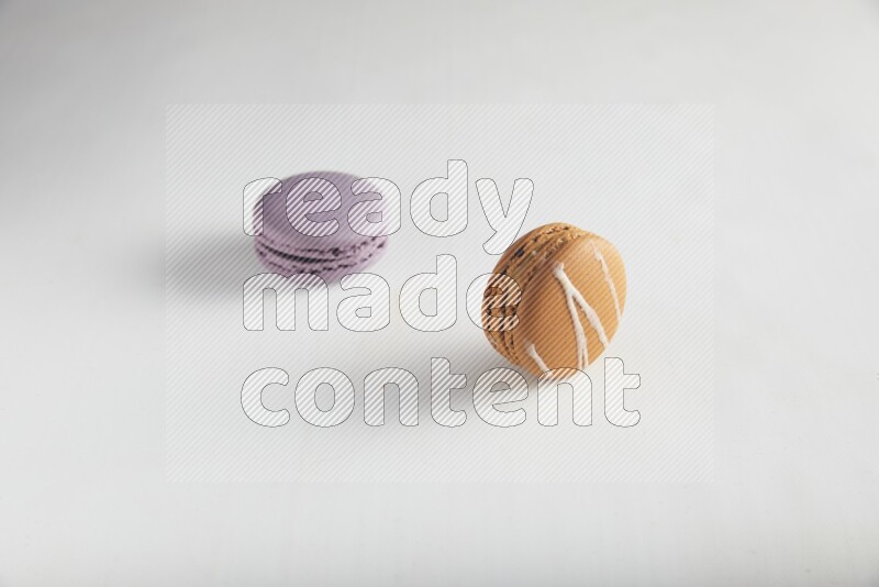 45º Shot of of two assorted Brown Irish Cream, and Purple Blueberry macarons on white background