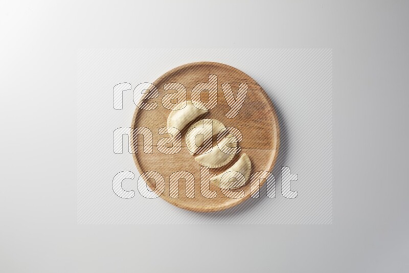Four Sambosas on a wooden round plate on a white background
