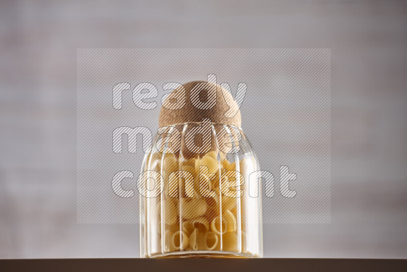 Raw pasta in glass jars on beige background