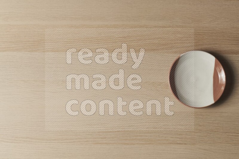 صحن فخاري متعدد الألوان على خلفية خشبية فاتحة