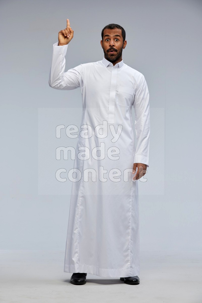 Saudi man Wearing Thob standing interacting with the camera on Gray background