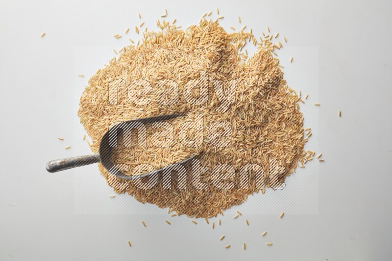 Top-view of a long grain brown rice, and shovel on white background
