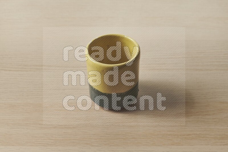 A multicolored pottery cup on light wooden background
