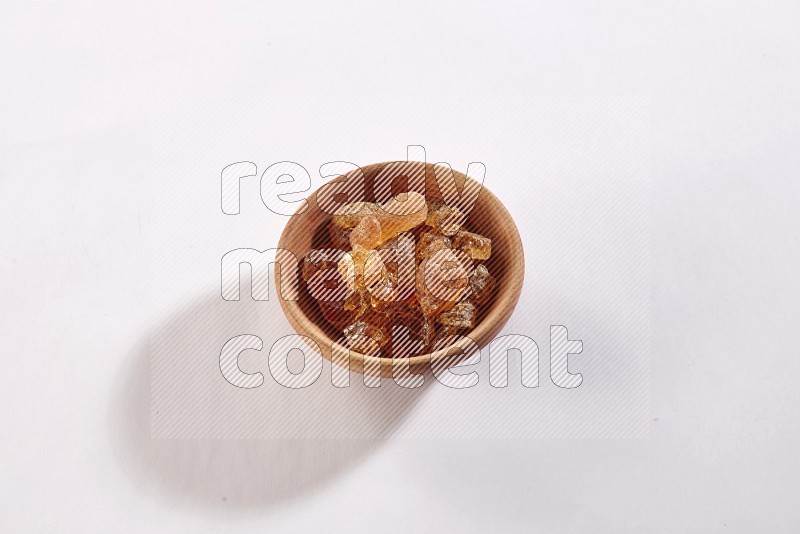 A wooden bowl full of gum arabic on a white flooring in different angles