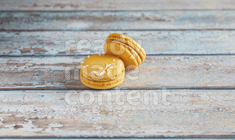 45º Shot of two Yellow Piña Colada macarons on light blue wooden background