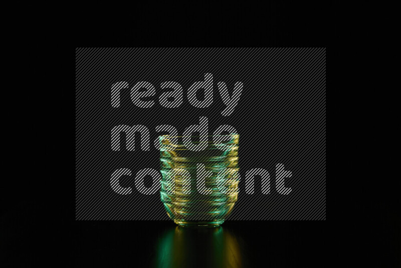 Glassware with rim light in green and yellow against black background