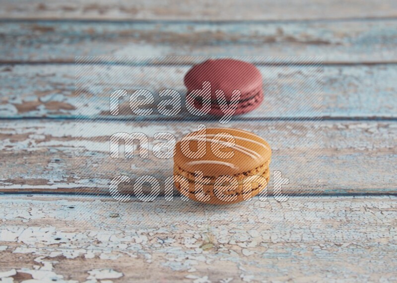 45º Shot of of two assorted Brown Irish Cream, and Red Cherry macarons  on light blue background