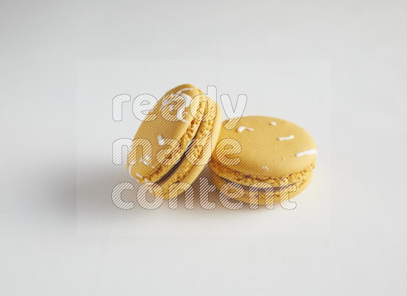 45º Shot of two Yellow Piña Colada macarons on white background