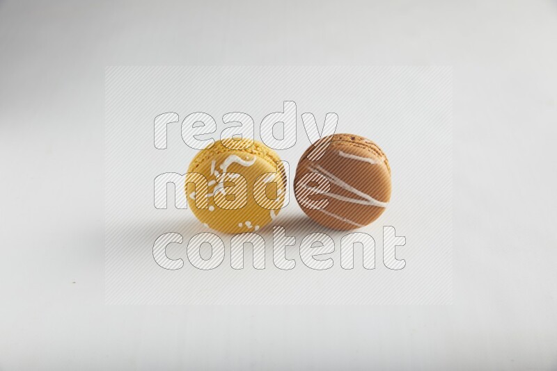 45º Shot of of two assorted Brown Irish Cream, and Yellow Piña Colada macarons on white background