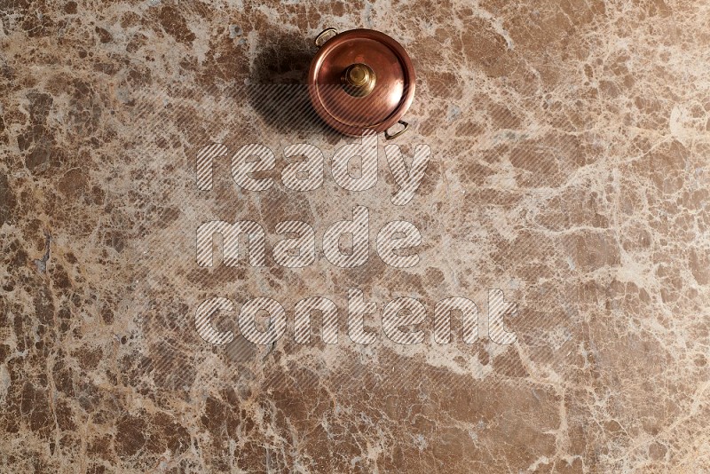 Top View Shot Of A Small Copper Pot On beige Marble Flooring