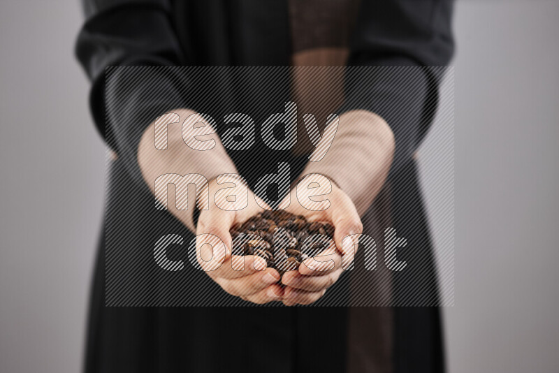 Woman in abaya holding different kinds of coffee beans in different positions