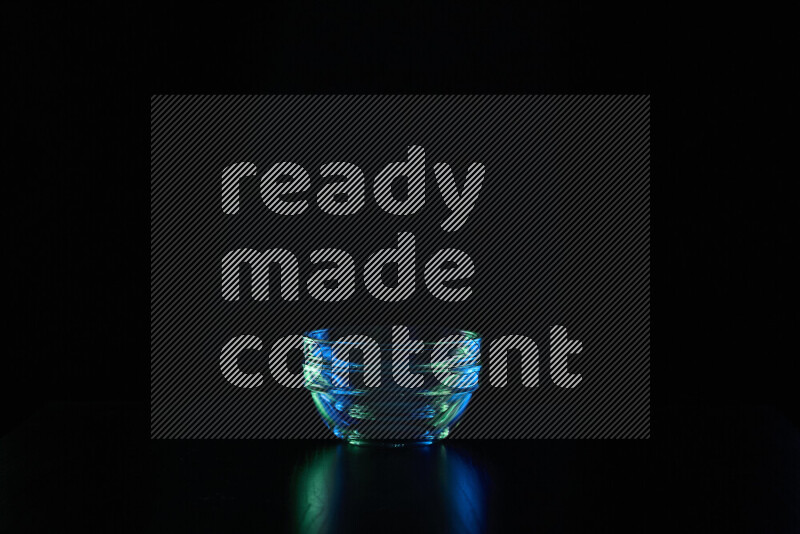 Glassware with rim light in blue and green against black background