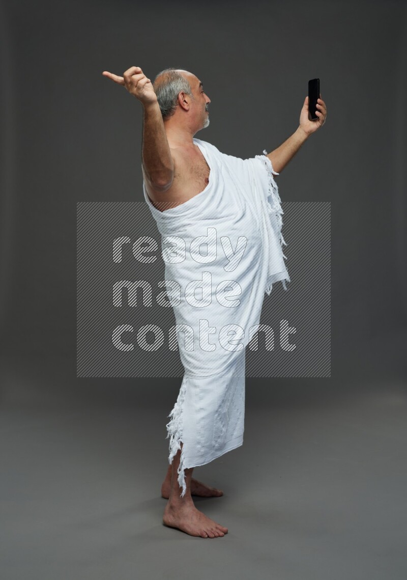 A man wearing Ehram Standing taking selfie on gray background