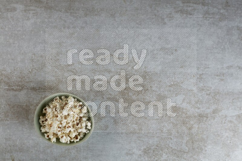 popcorn in green bowl on a grey textured countertop