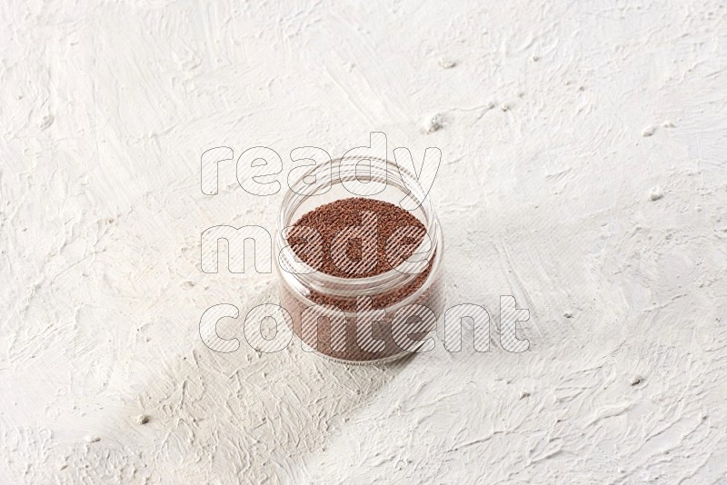 A glass jar full of garden cress seeds on a textured white flooring