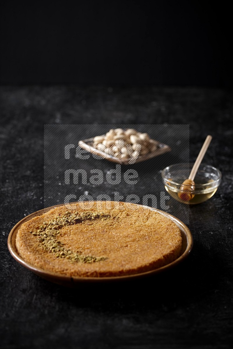 Konafa with nuts and honey in a dark setup